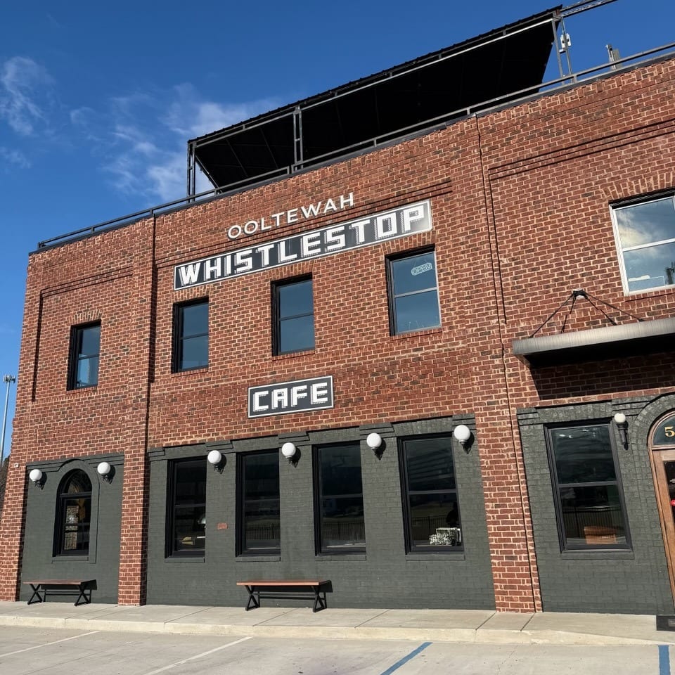 The Ooltewah Whistlestop Cafe, a brick building with dark gray lower walls and large windows.